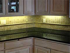 This custom tile backsplash reflects beautifully against the stone countertops in this kitchen remodel