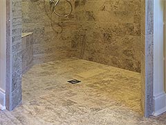 This barrier-free shower stall showcases custom tile work and the seamless floor is designed to quickly draw water to the drain without the need for a barrier or curb