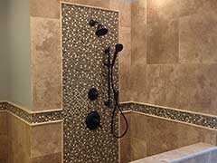 This custom Travertine shower features a Raincan shower head and intricate custom tile work